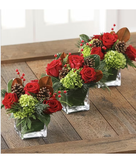 red and white floral arrangement with holiday accents and pinecones in a wicker basket