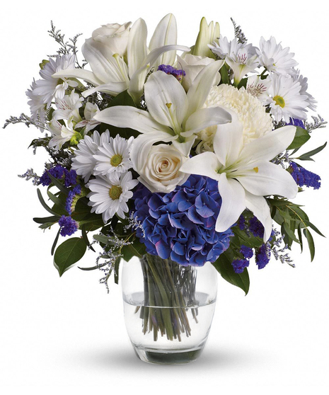 blue hydrangeas and white flowers including daisies and lilies in blue vase